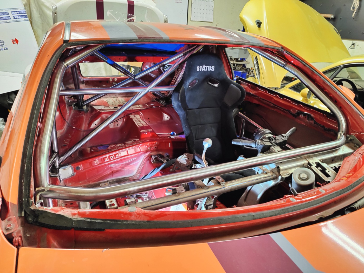 Cage in an orange track car, seen from the rear with the seat fitted